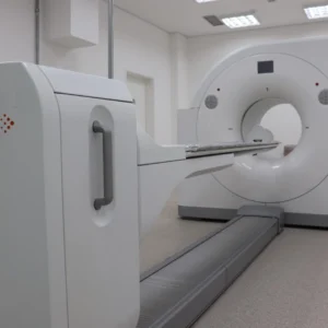 Equipamento de PET-CT branco instalado em sala clínica com piso claro e iluminação de teto.